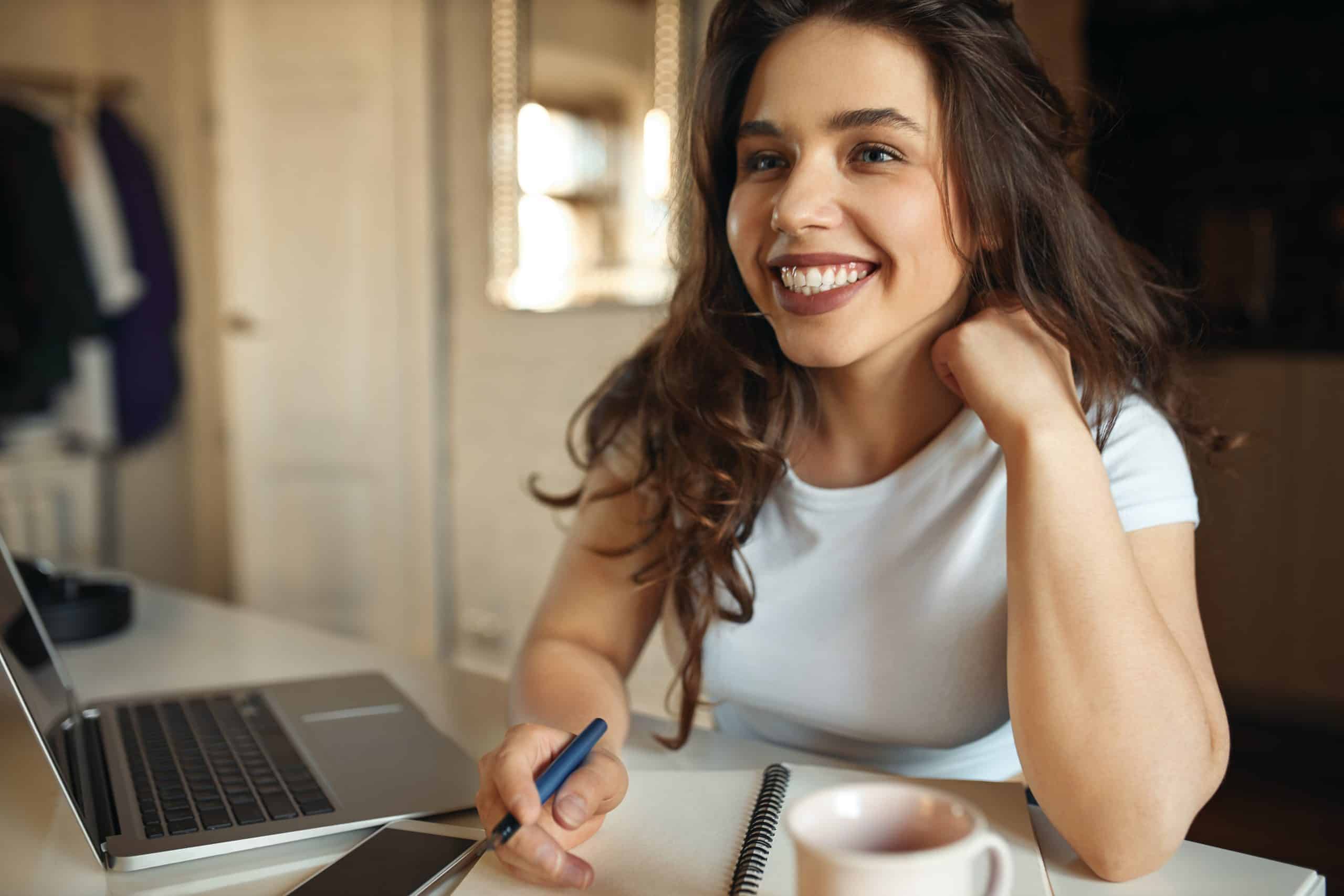 happy-young-plus-size-woman-making-notes-in-her-copybook-using-wireless-internet-connection-on-laptop-scaled-2